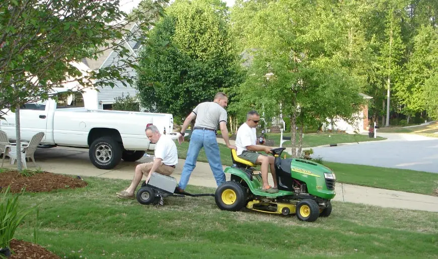 men using lawn tractor with lawn aerator attachment