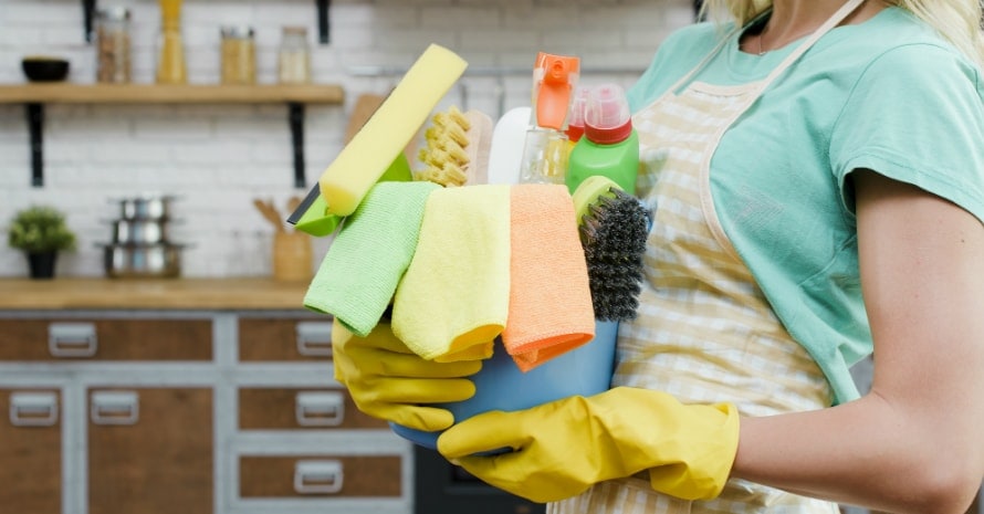 woman-wearing-yellow-rubber-gloves-holding-cleaning-products-home