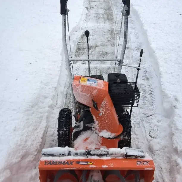 On the snow is a Yardmax 2-Stage Snow Blower