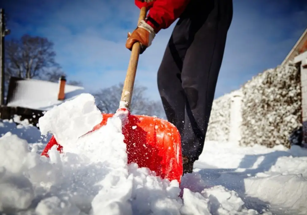 Human shovels snow with orange shovel